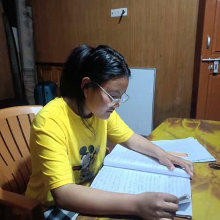 Una persona joven estudia en una mesa, rodeada de libros y cuadernos.