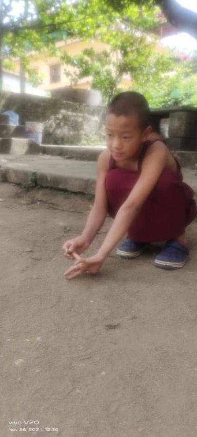 Niño sentado en el suelo, jugando con algo en la tierra.